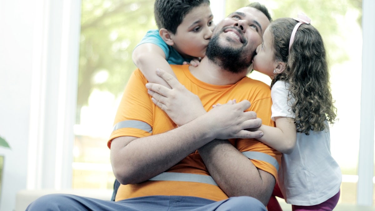 A man sitting on a couch hugging a little girl